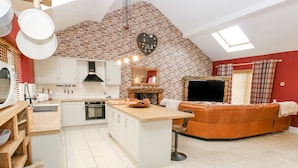 A modern kitchen with a central island, a fireplace, and a cozy seating area with a sofa and a TV.