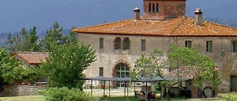 A rustic building with a tiled roof, arched windows, and a small tower-like structure.