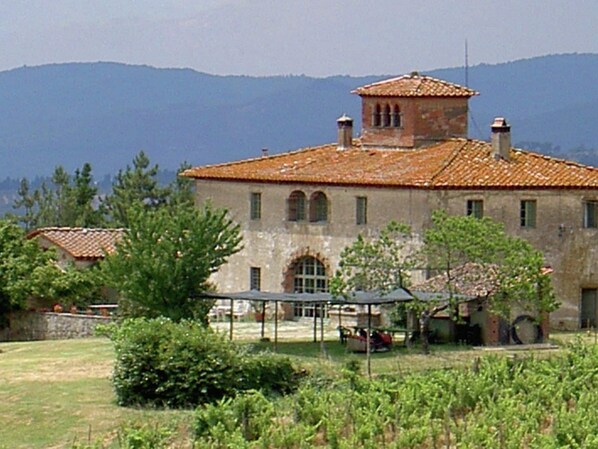 A rustic building with a tiled roof, arched windows, and a small tower-like structure.