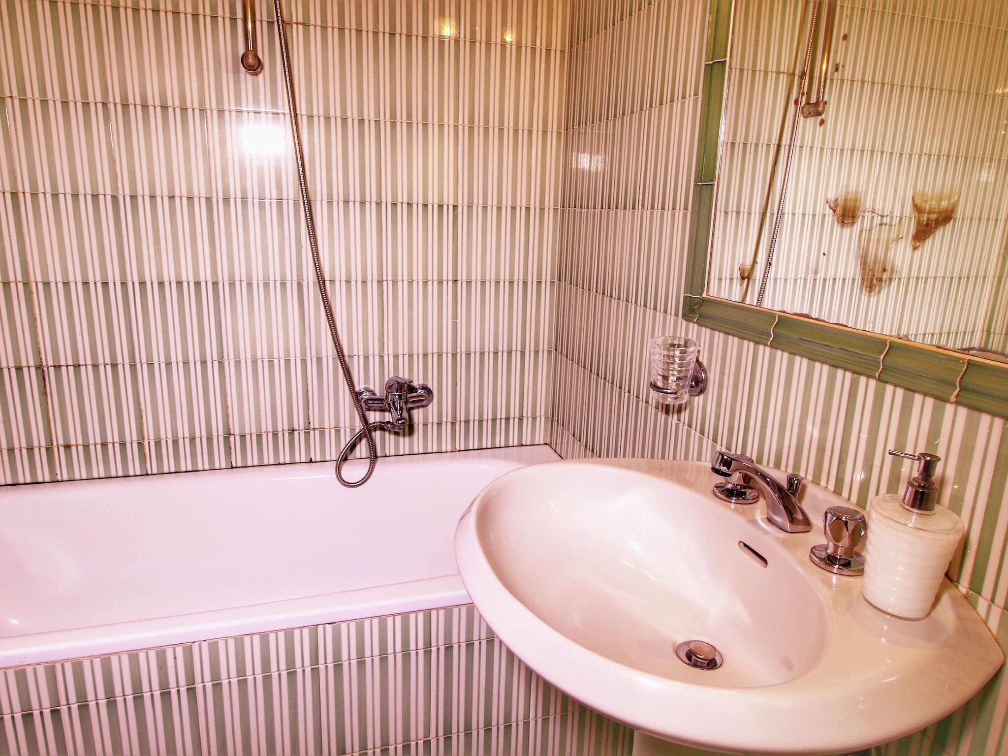 A bathroom with a bathtub, a sink, and a mirror.