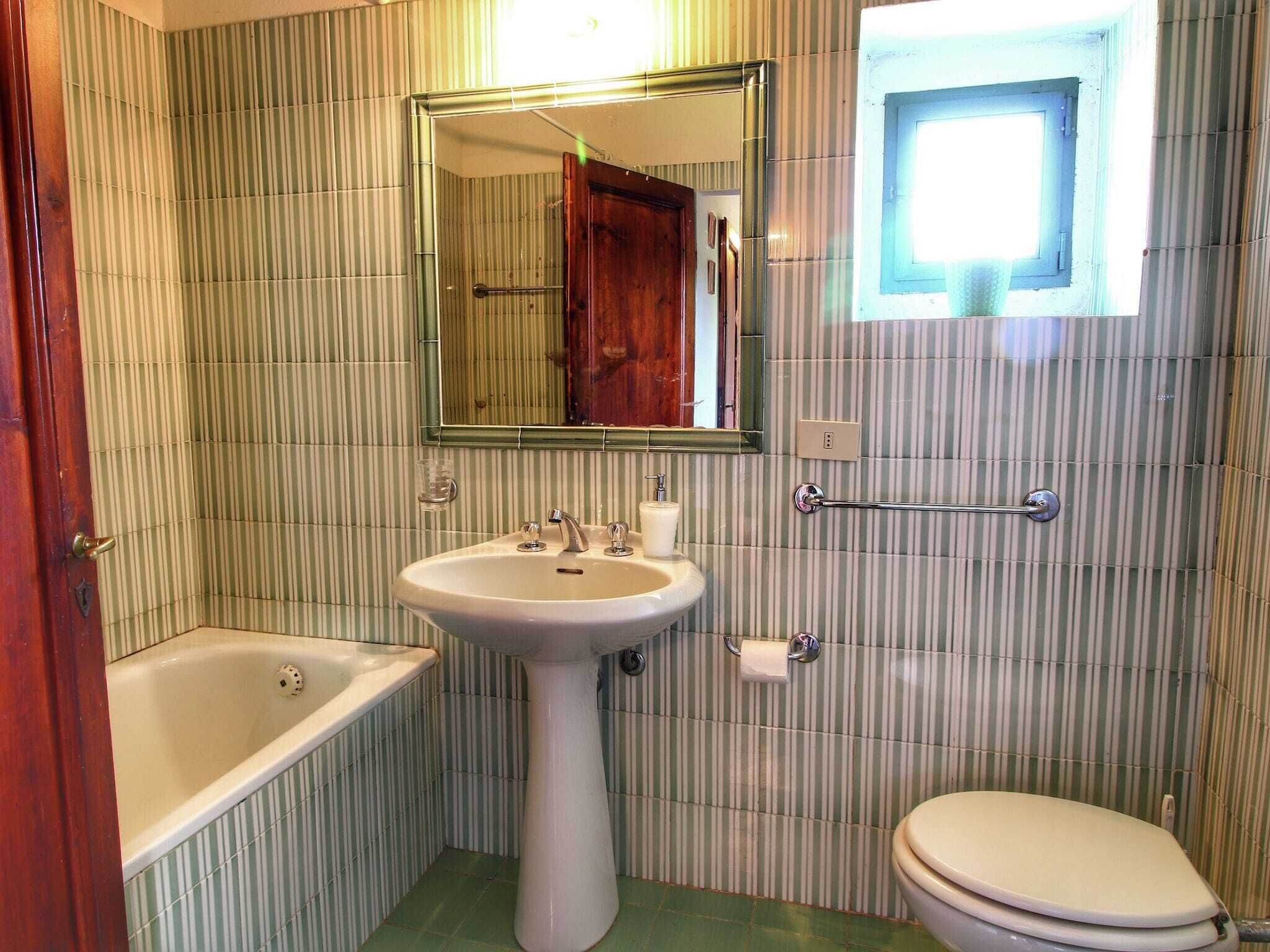 Une salle de bain comprenant un lavabo sur colonne, une baignoire, des toilettes, un miroir et une fenêtre.
