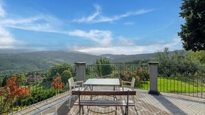 Une terrasse avec une table et des chaises, un sol en pierre et une vue sur un paysage montagneux.