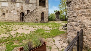 Un bâtiment en pierre doté de fenêtres en arc de cercle et d’une cour avec de l’herbe et un jardinière.