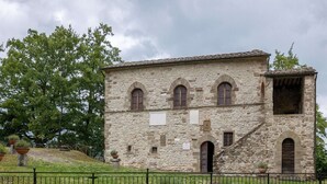 Un edificio de piedra con ventanas arqueadas y una escalera que conduce a un nivel superior.