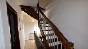 A staircase with wooden handrails and a tiled floor leading to a landing. - Hillview Langhe Apartment (Belvedere Langhe)