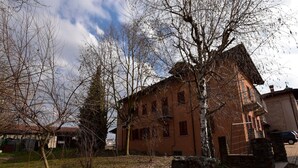 A rustic building with a brick facade, surrounded by bare trees and a stone wall. - Hillview Langhe Apartment (Belvedere Langhe)