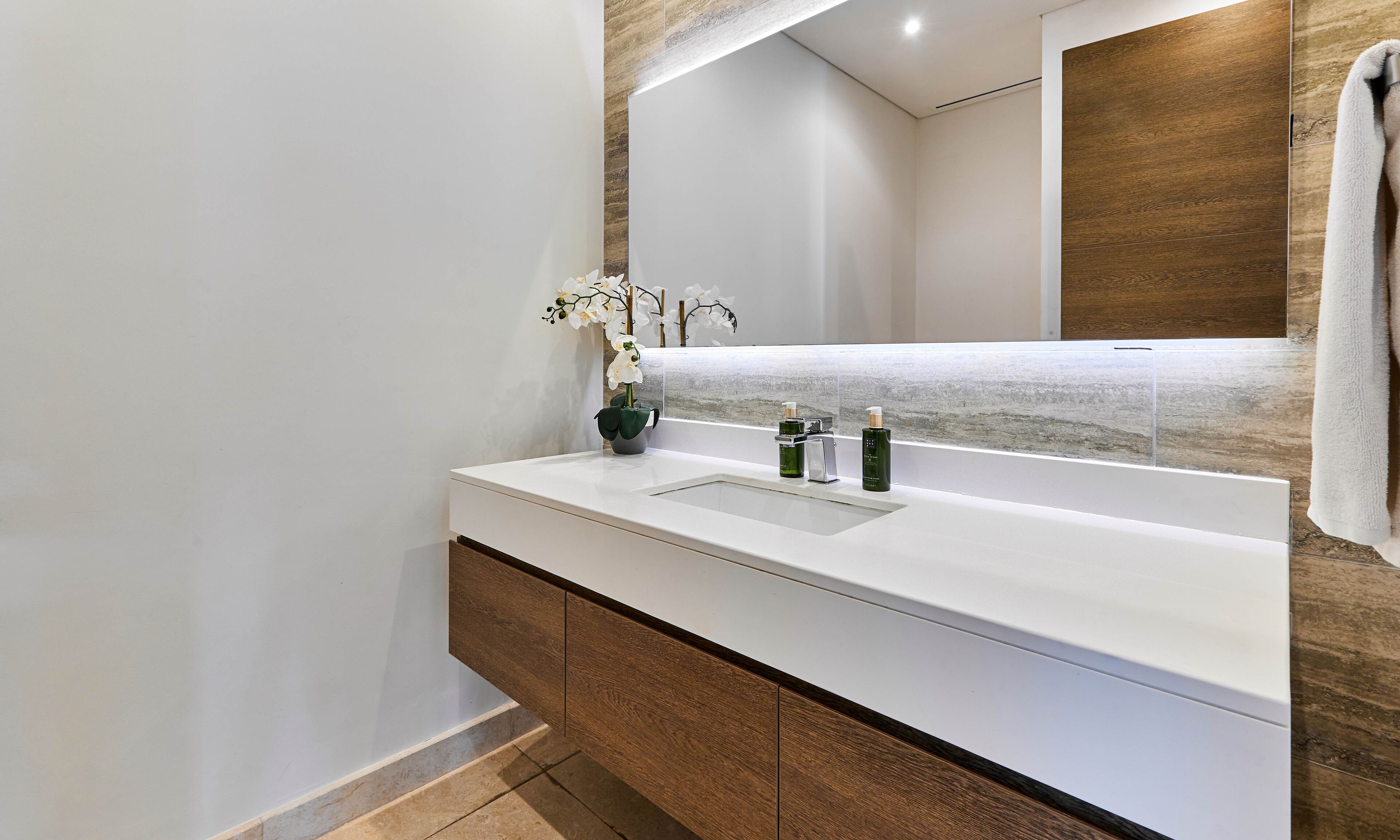 A modern bathroom with a white vanity, a large mirror, and a wooden accent wall.