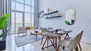 Un comedor moderno con un ventanal grande, una mesa de comedor dispuesta con platos y vasos, y un sofá con cojines.