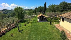 A rural property with a small wooden structure, a well-maintained lawn, and surrounding trees. - Apartment in Sabina with Panoramic Views (Selci)
