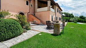 Une maison à deux étages avec un chemin de pierre menant à un patio aménagé avec du mobilier d’extérieur.