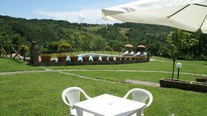 Eine Außenpatio mit Pool, weißen Stühlen und Sonnenschirmen.