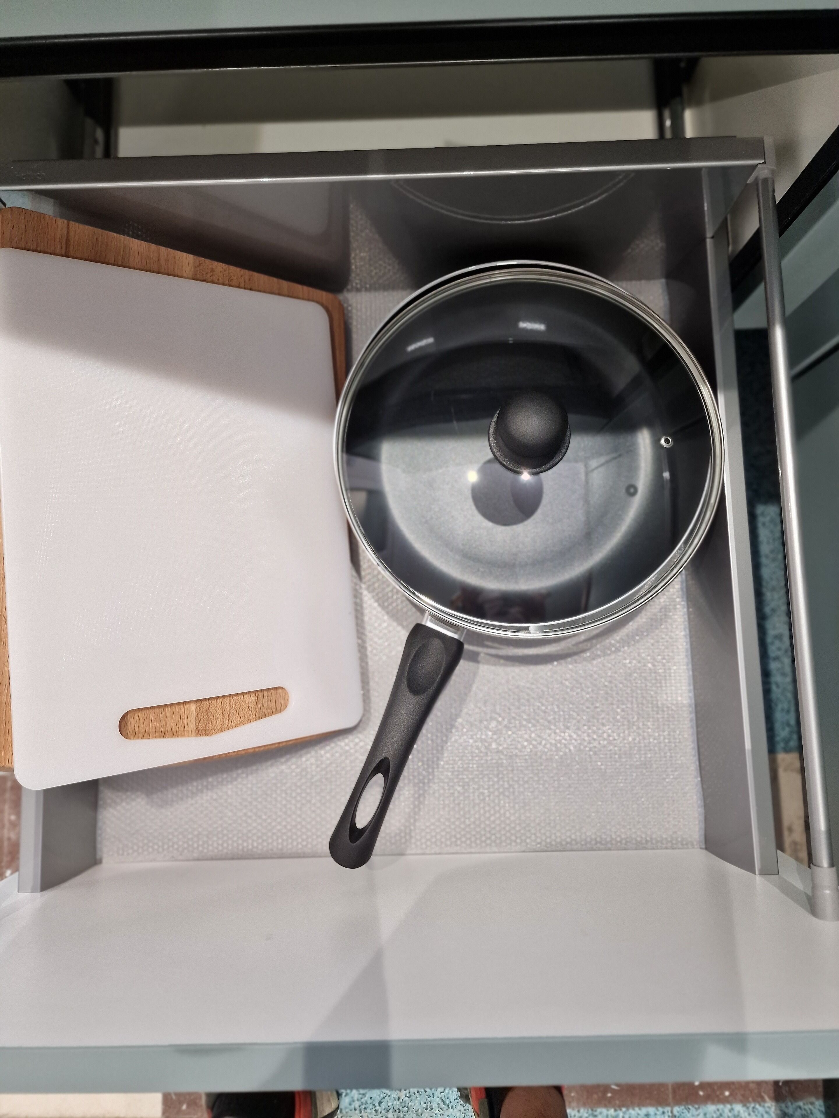 A kitchen with a white cutting board and a pot on the counter.