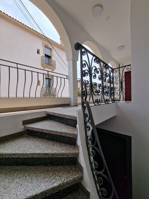 A staircase with a black wrought iron railing leading to a balcony.