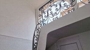 Een trap met een decoratieve metalen balustrade en een witte deur onderaan.