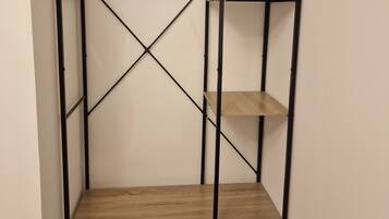 A walk-in closet with a wooden floor, metal frame, and multiple shelves.