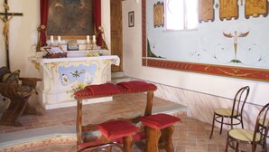 Een kerkinterieur met een houten altaar, banken en religieuze schilderijen.