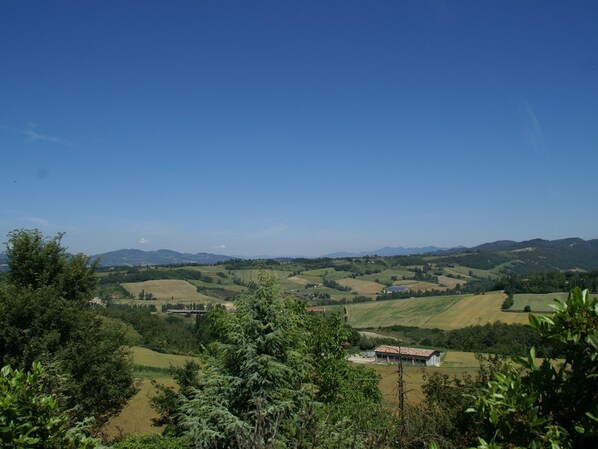A rural landscape with rolling hills, a clear blue sky, and a small building with a red roof.