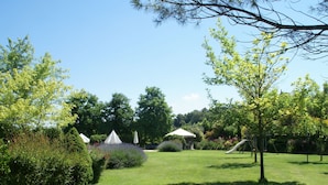 Un jardin bien entretenu, avec une pelouse verdoyante, plusieurs arbres et un petit pavillon.