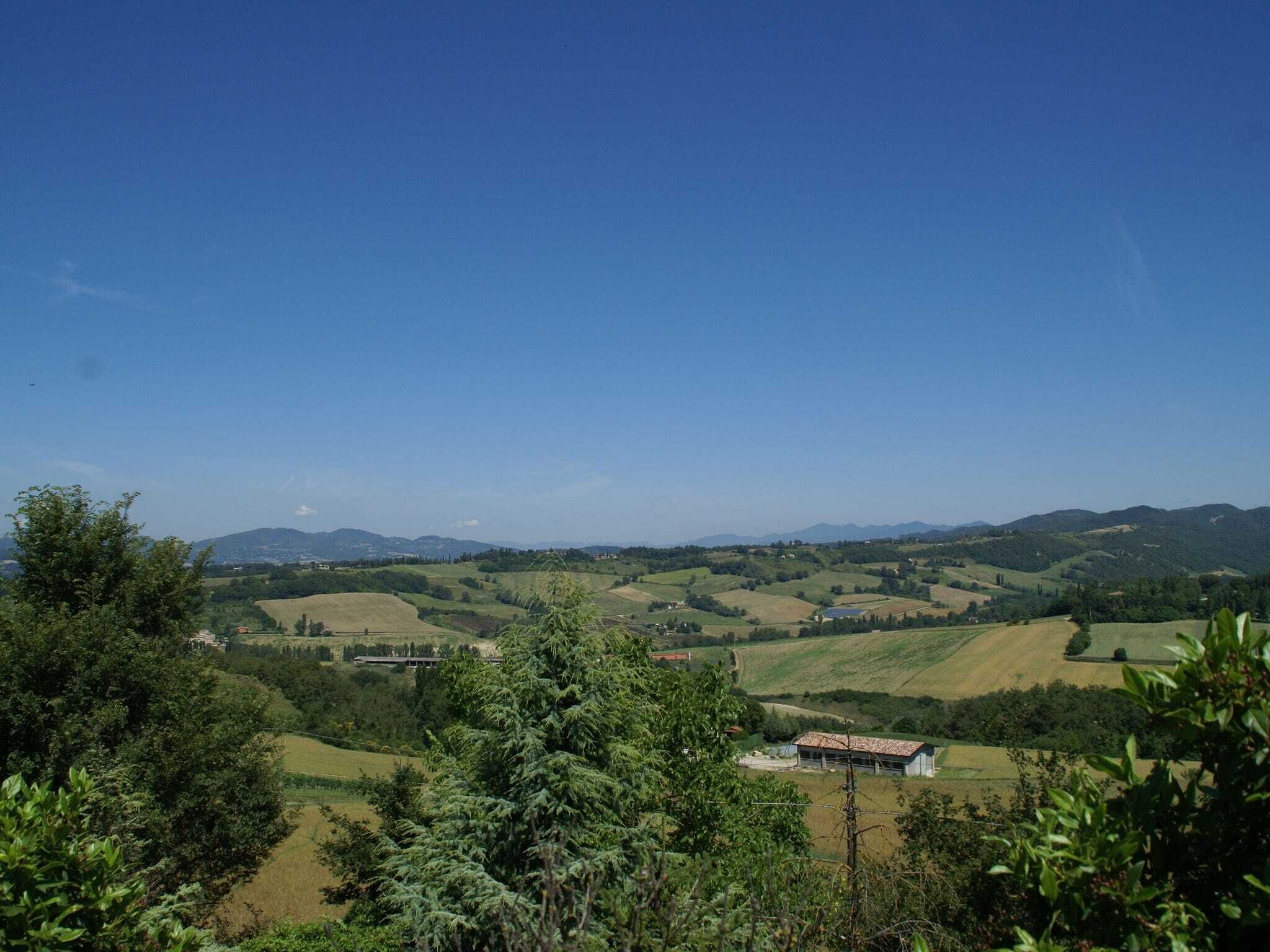 Un paysage rural avec des collines douces, un petit bâtiment et un ciel bleu dégagé.
