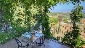 Una terraza con una mesa para dos, rodeada de follaje y con vistas a un paisaje pintoresco.