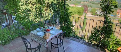 Una terraza con una mesa para dos, rodeada de follaje y con vistas a un paisaje pintoresco.