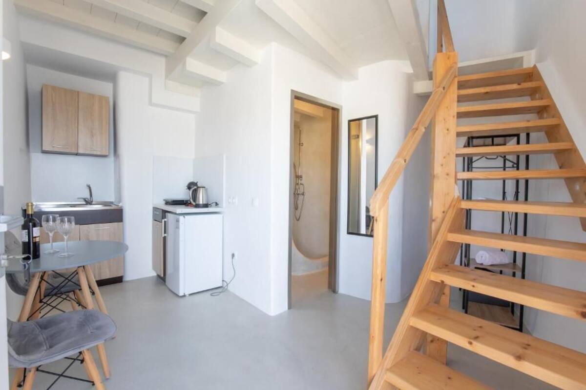 Une cuisine moderne avec un coin repas, un escalier en bois et une salle de douche.