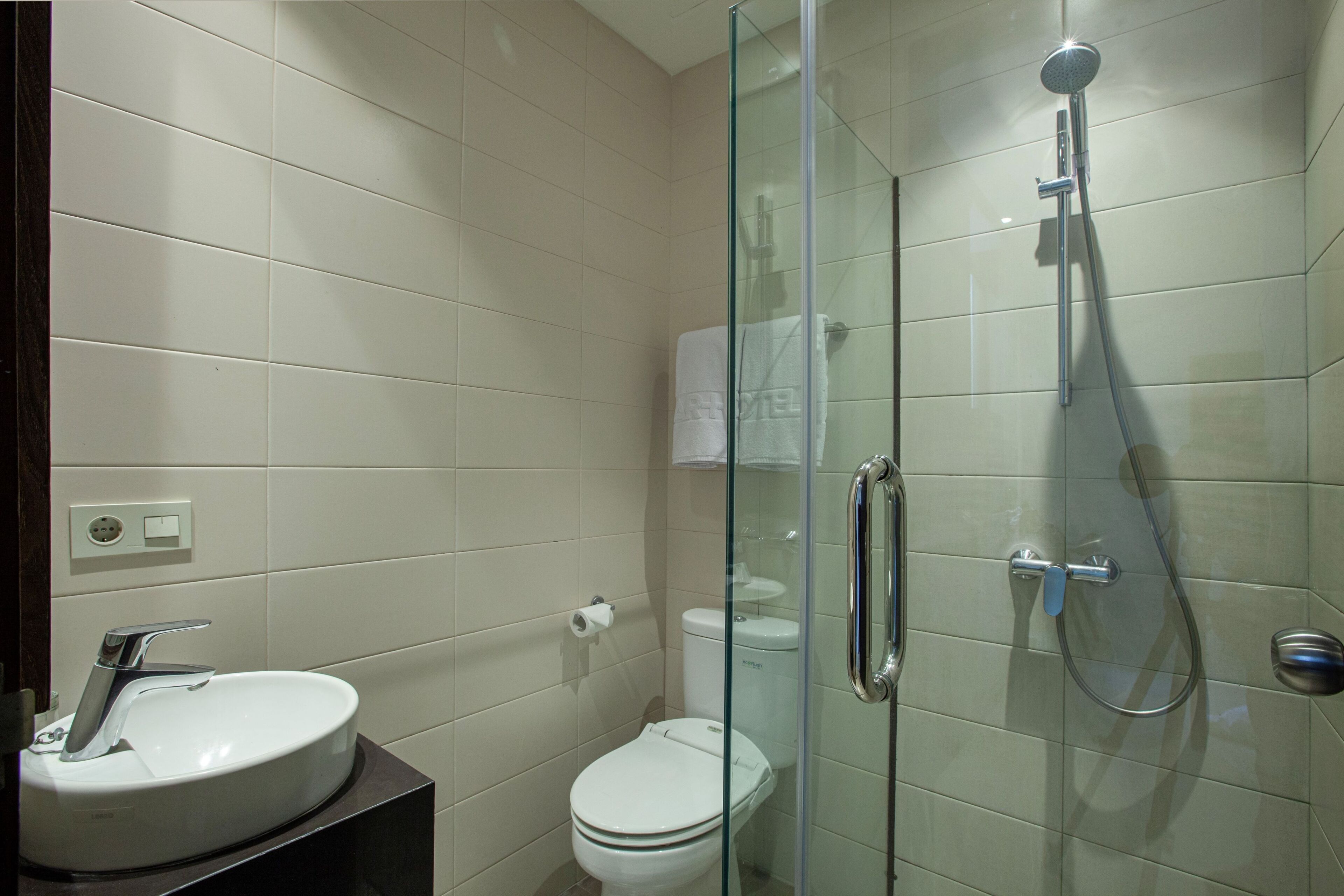 Une salle de bain moderne avec une douche à parois de verre, un lavabo blanc et des toilettes.