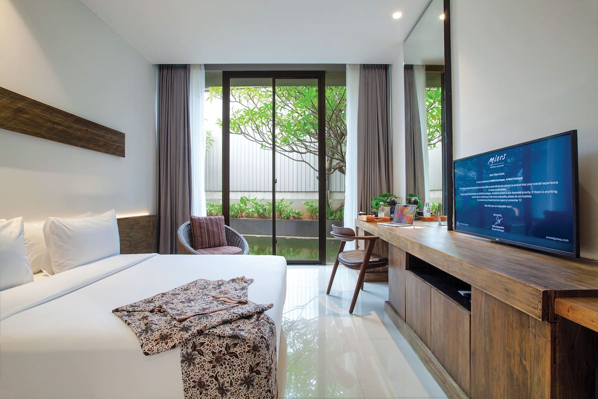 A modern hotel room with a large bed, a desk, and a television.