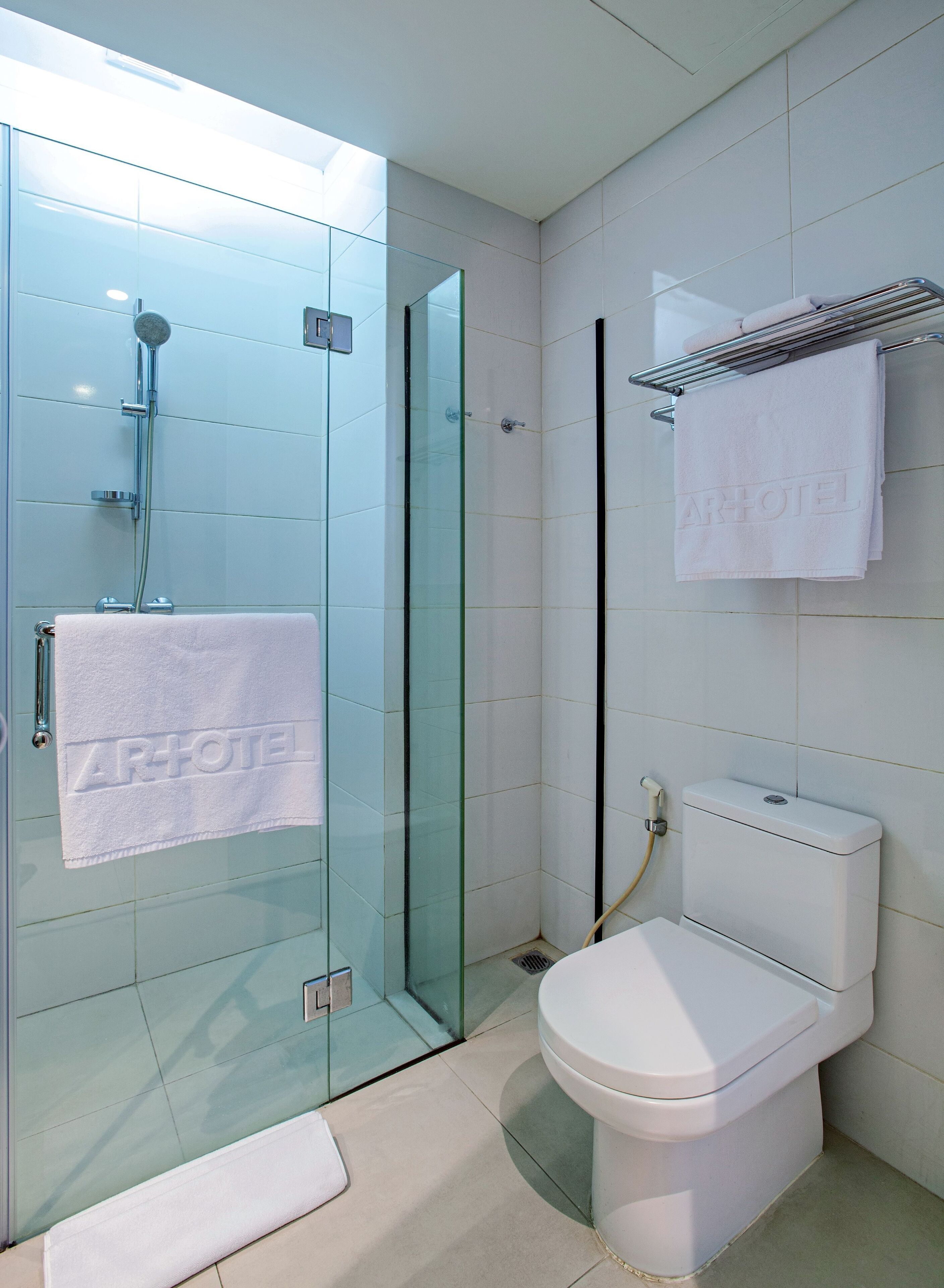 A modern bathroom with a glass shower enclosure, a toilet, and a towel rack.