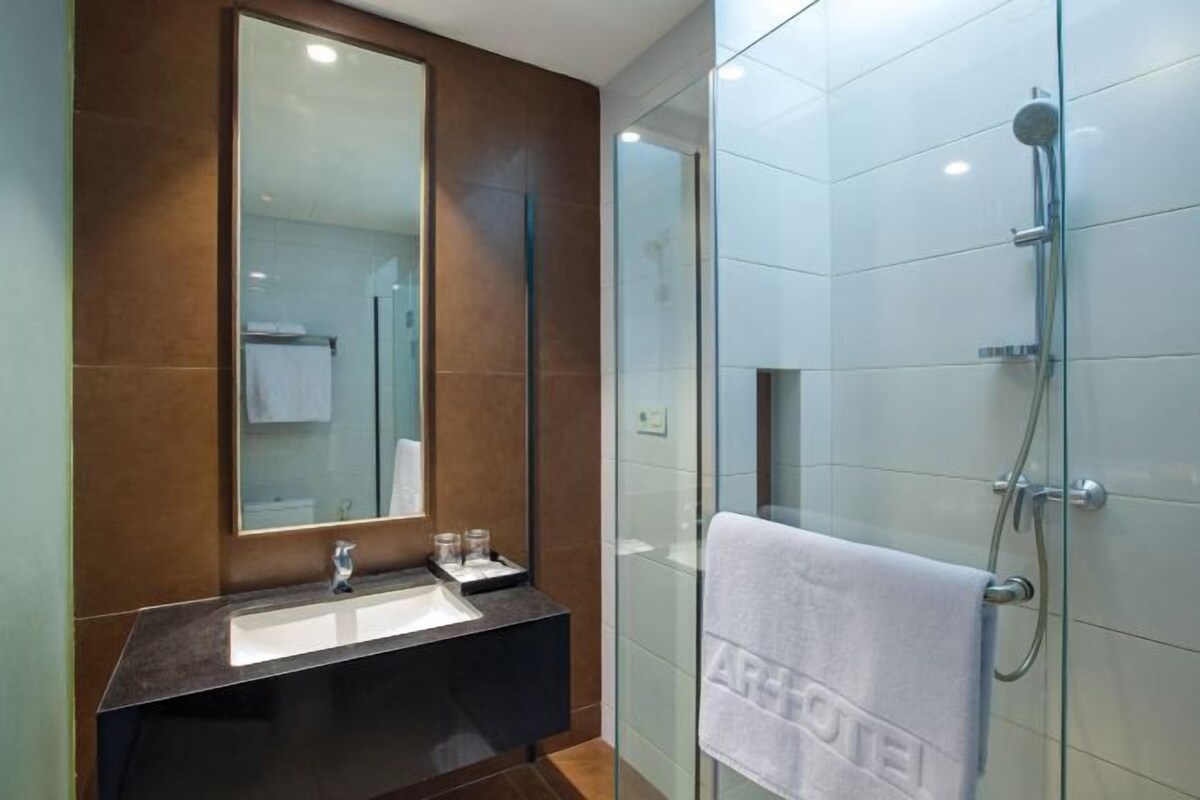 A modern bathroom with a dark marble vanity, a large mirror, and a glass shower enclosure.