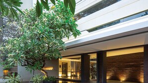 Um edifício moderno com fachada de vidro, um espelho de água e plantas em vasos.