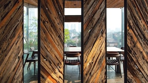 Um interior moderno com painéis de madeira, sala de jantar com cadeiras e mesa, e janelas amplas com vista para a cidade.
