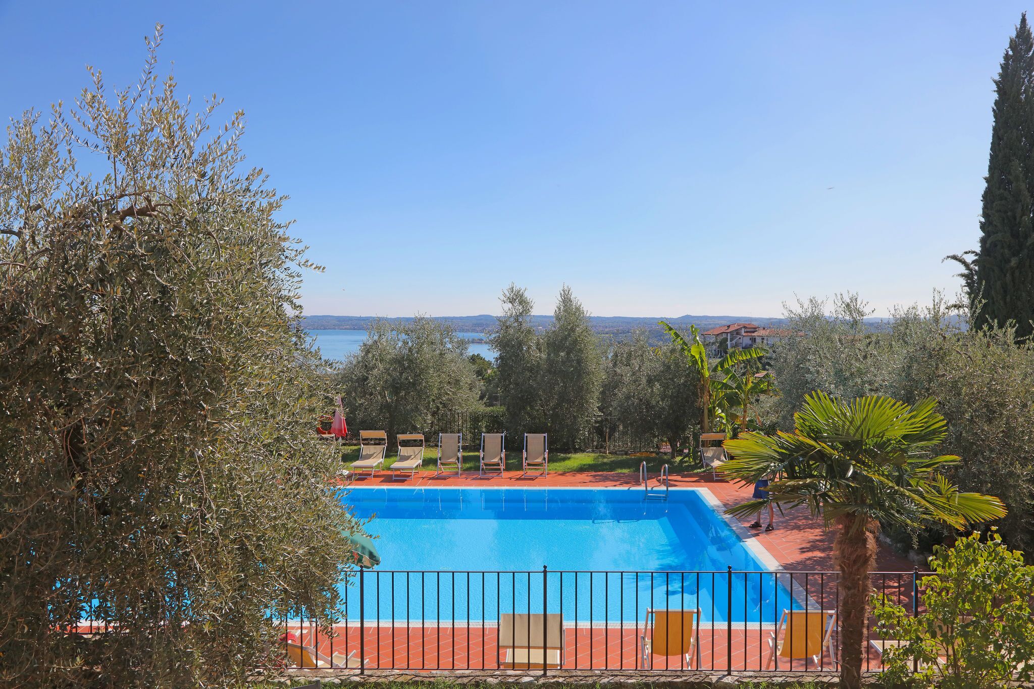 Una piscina con sillones de descanso y vistas al mar.