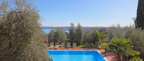 A swimming pool with lounge chairs and a view of the sea.