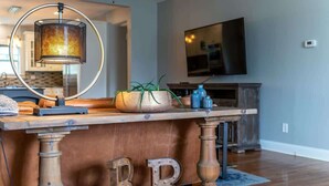 A wooden bar area with a round table, a lamp, and decorative elements including a plant and letter 'B' and 'R' on the floor. - Downtown Walk Around (Blue Ridge)