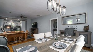 A dining area with a wooden table set for six, white chairs, and a chandelier. - Downtown Walk Around (Blue Ridge)