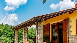 A house with a stone facade, a wooden porch, and a tiled roof. - Holiday Home in Tuscany with Pool & Olive Trees (Montecatini Terme)