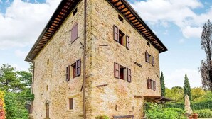 A stone building with a sloped roof and multiple windows, surrounded by greenery. - Scenic Stay in Restored Retreat (Arezzo)