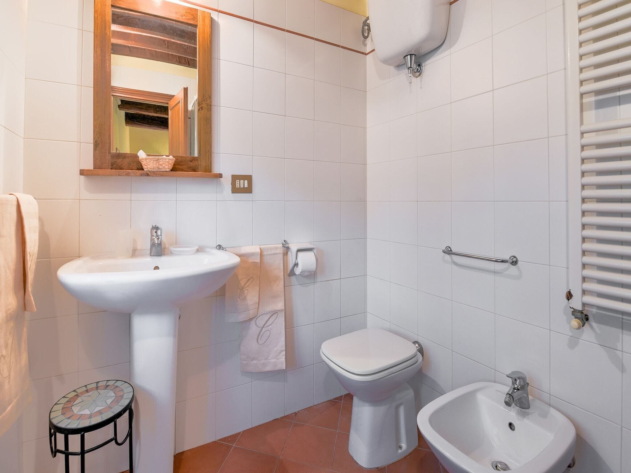 Et badeværelse med et konsolbord, toilet, bidet og et lille rundt bord.