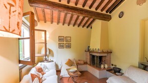 A cozy room with a fireplace, white furniture, and a rustic ceiling. - Scenic Stay in Restored Retreat (Arezzo)