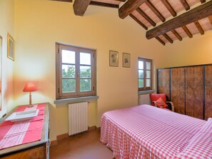 Een slaapkamer met twee bedden, een raam, een radiator en een garderobe.