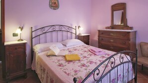 Ein Schlafzimmer mit einem Bett, zwei Nachttischen, einer Kommode, einem Stuhl und einer Deckenleuchte.