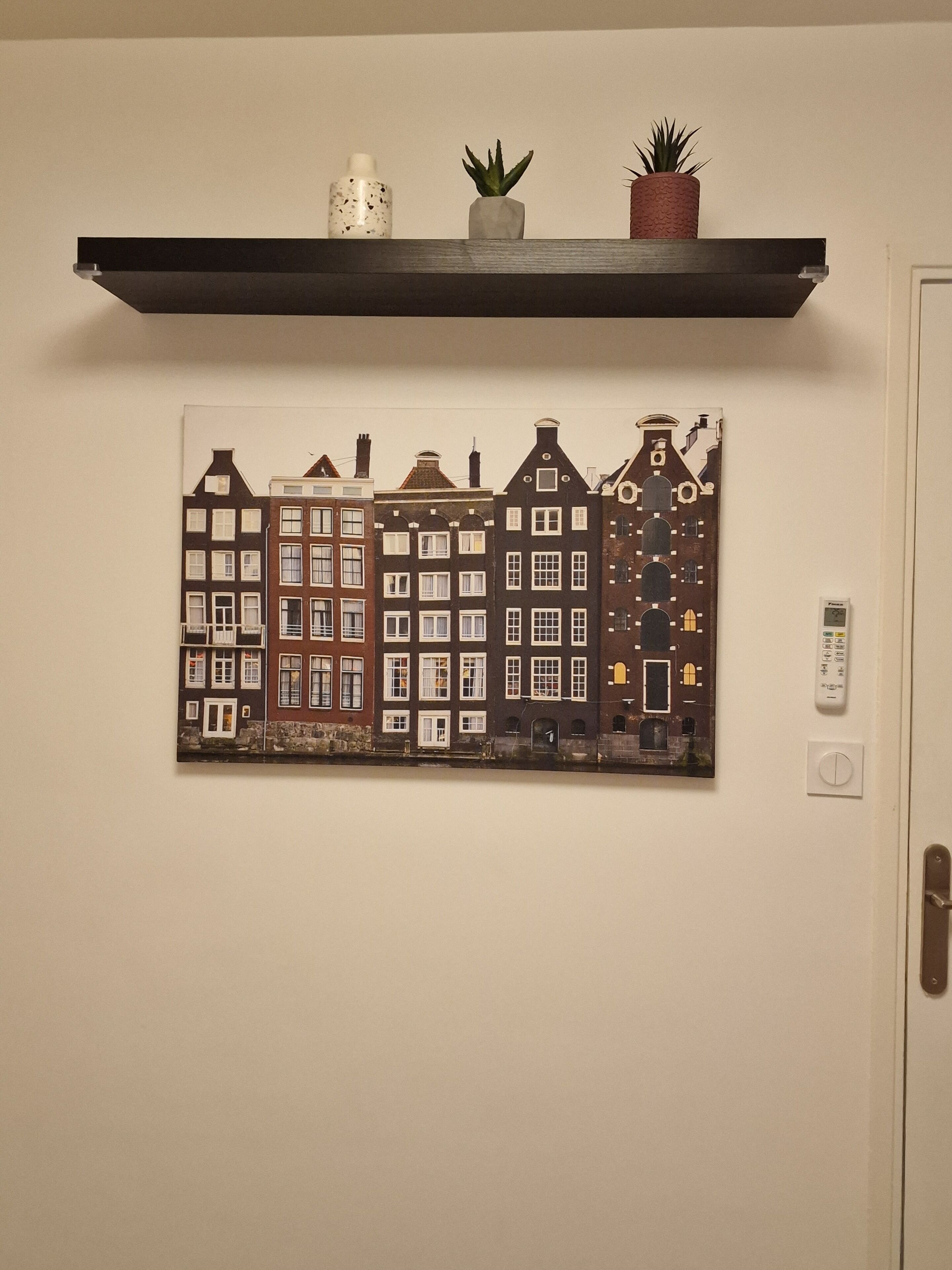 Una estantería con adornos y una obra de arte enmarcada de un pueblo europeo.