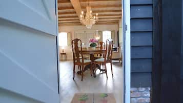 A wooden dining room with a chandelier, a welcome mat, and a view into the house.