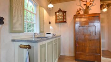 Une cuisine avec des meubles de rangement en bois, une fenêtre avec des volets et une tête de cerf décorative accrochée au mur.