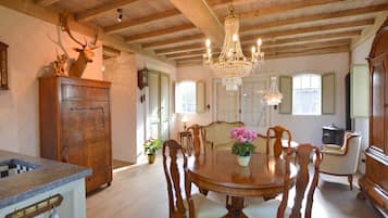 A dining room with a wooden table and chairs, a chandelier, and a deer head on a cabinet.