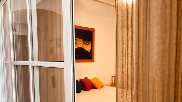 Quarto de hotel com cama, um quadro na parede e janela com cortinas.