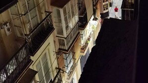 Um edifício com várias andares, varandas, uma escadaria e uma rua estreita.