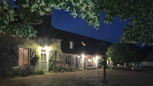 A rustic house with a stone facade, a wooden door, and a small porch area.