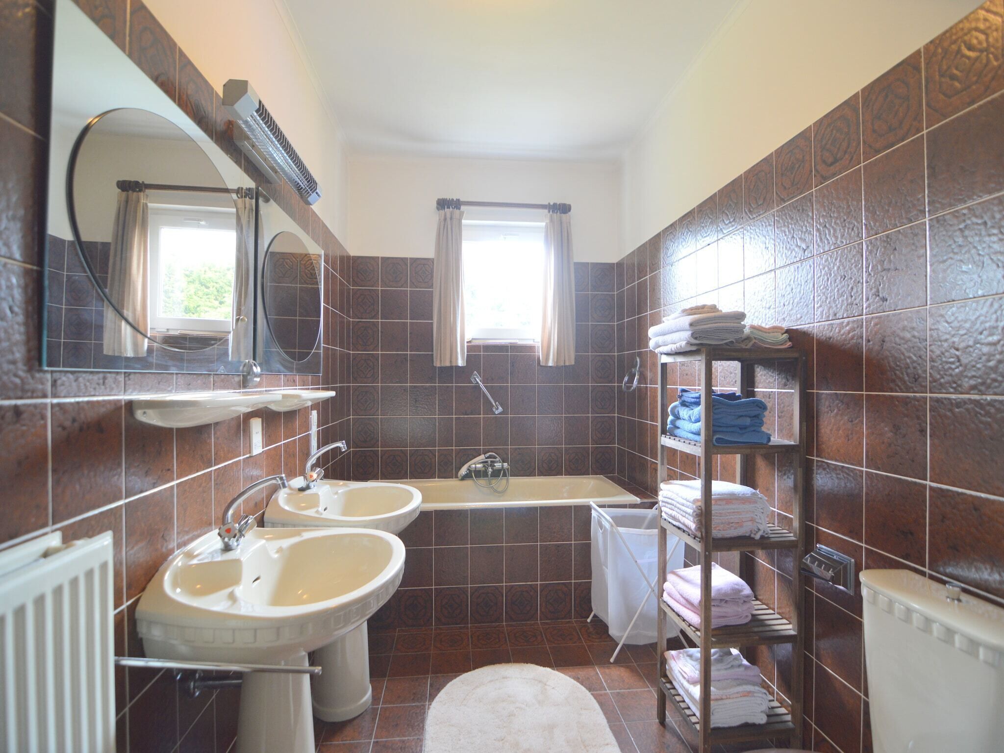 Ein Badezimmer mit zwei Waschbecken, einem Spiegel, einem Fenster und einem Handtuchhalter.